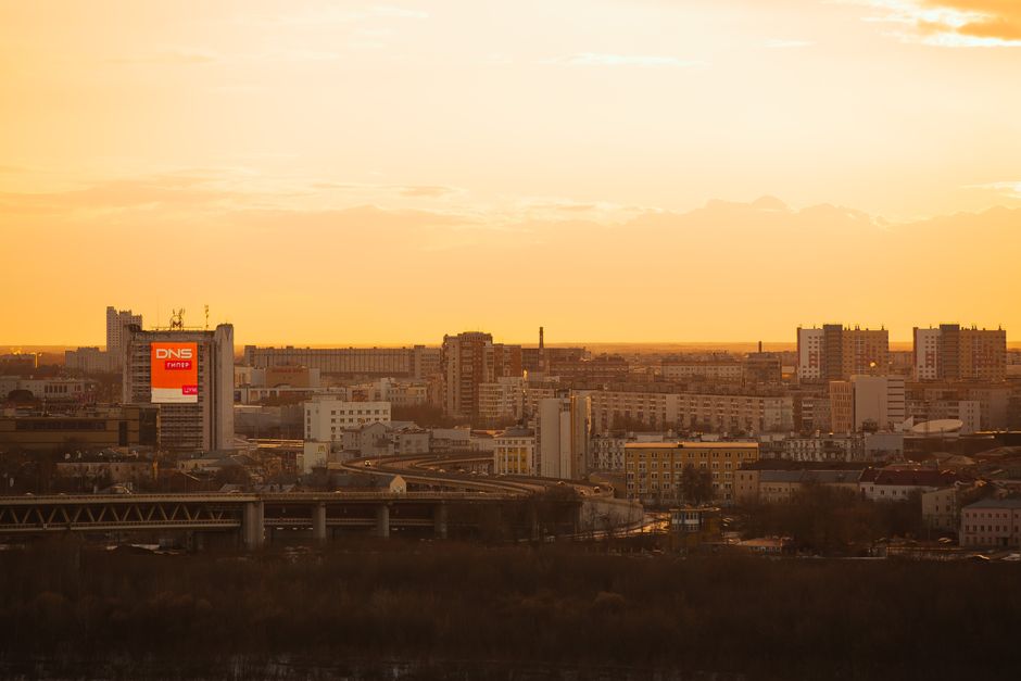 A vibrant city skyline at sunset featuring tall buildings with a warm orange sky.