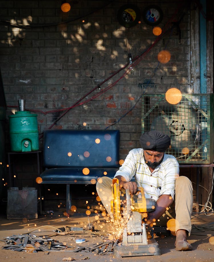 Man In Headwear Cutting Metal With Saw