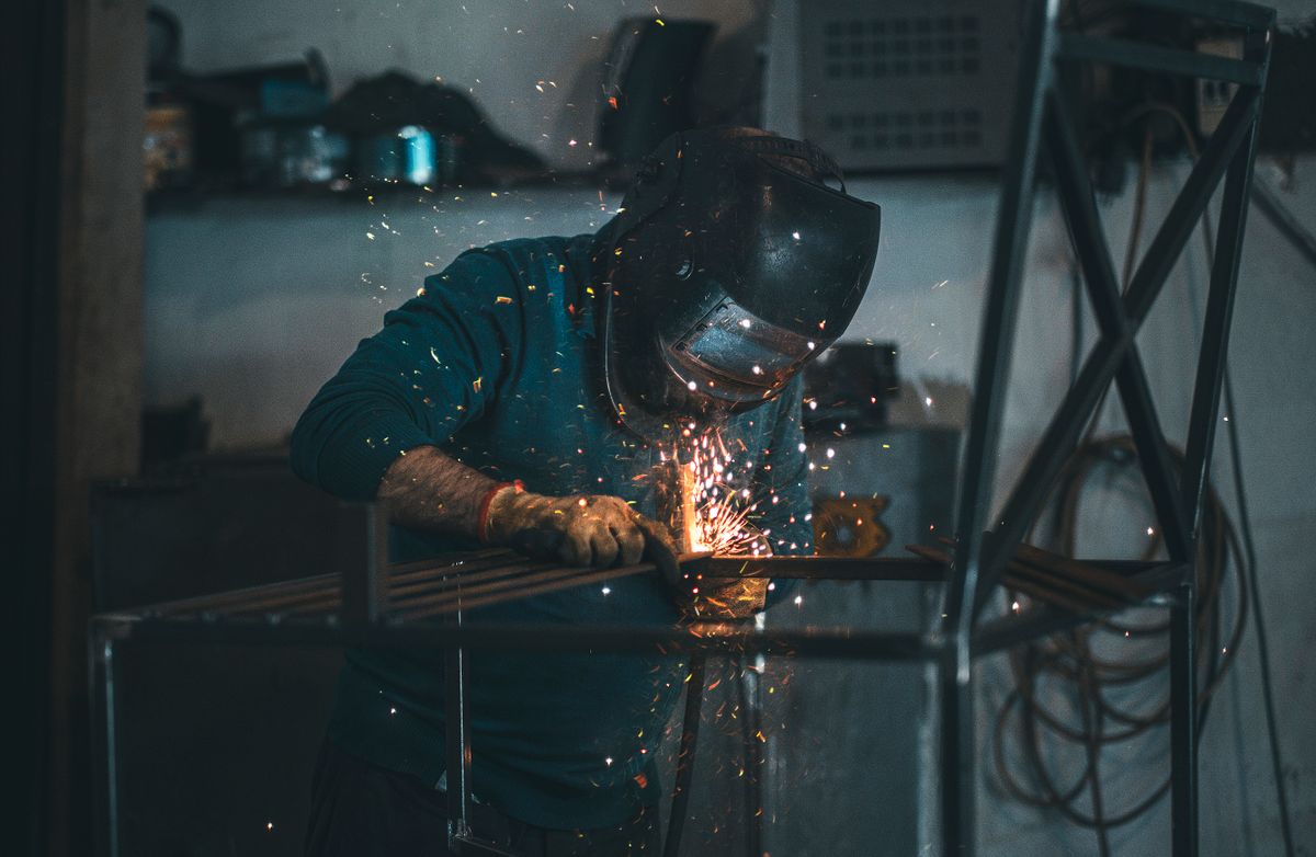 Welder at work in a steel workshop with bright sparks