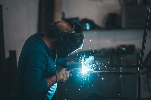 Free A skilled welder works with precision, creating sparks during metal fabrication in an industrial workshop. Stock Photo