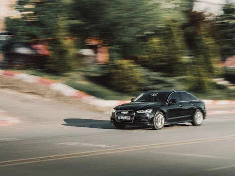 Dynamic shot of a black Audi car on a city road, emphasizing speed and motion.
