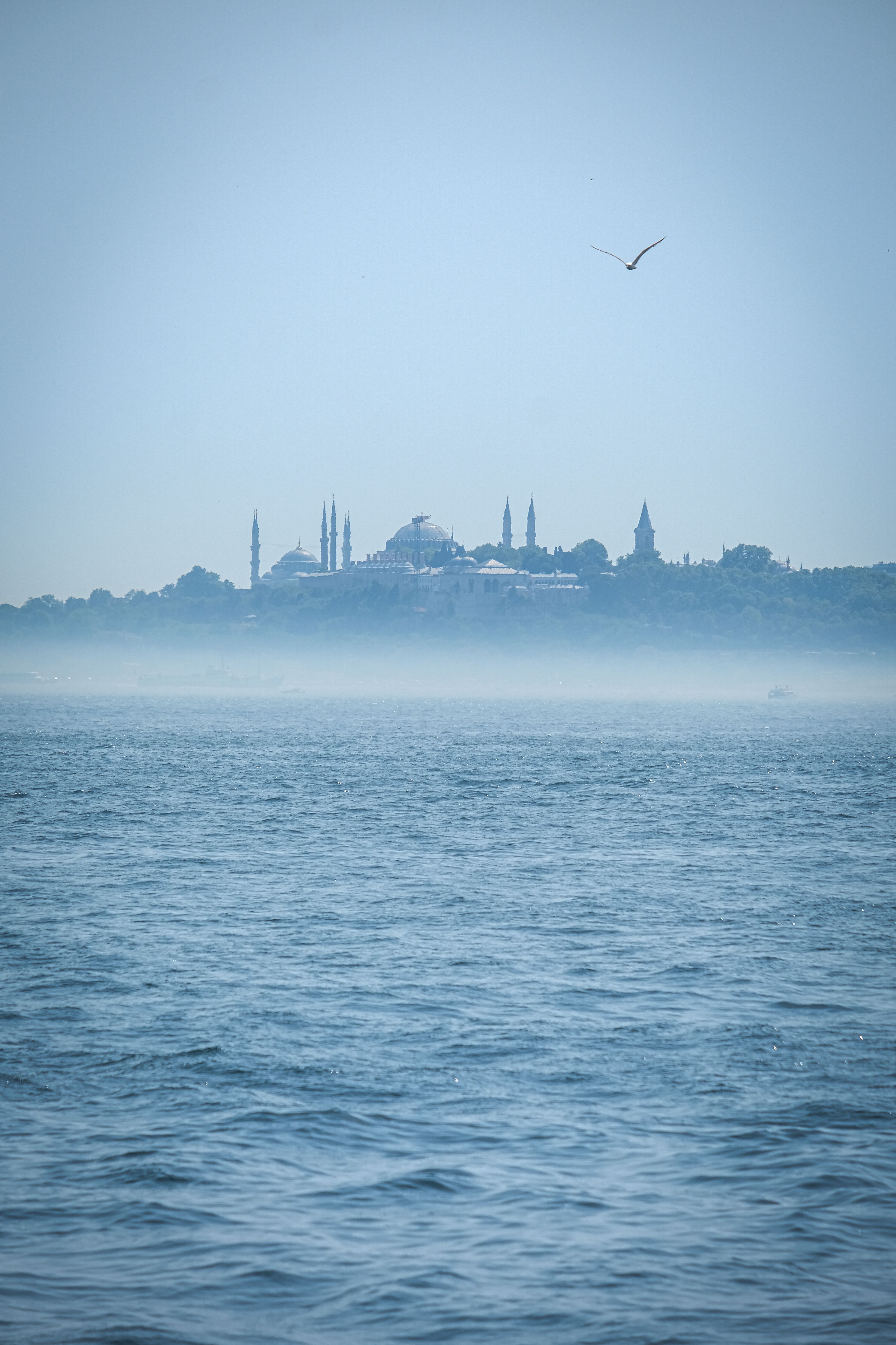 Misty horizon view of Istanbul's iconic skyline across the sea, showcasing a peaceful and serene atmosphere.