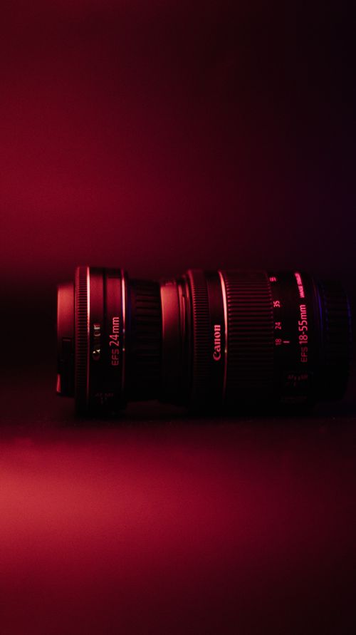 Free A close-up of a camera lens against a vibrant red background, highlighting its details. Stock Photo