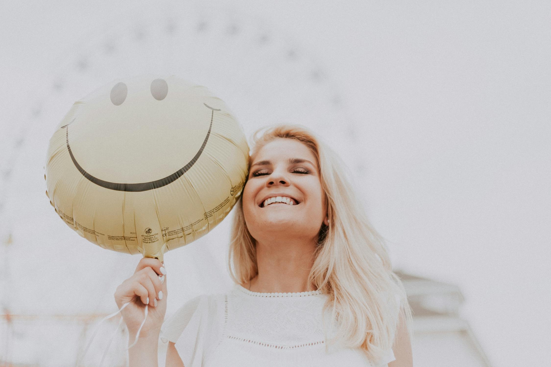 Image of a woman holding a smiley balloon 