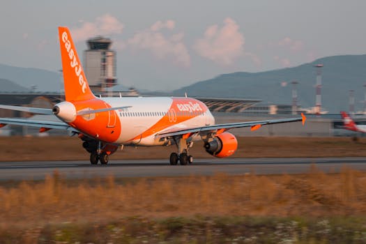 EasyJet aircraft taking off at an airport during sunset with visible control tower.