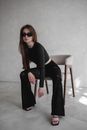 Woman in Black Long Sleeve Shirt and Black Pants Sitting on White Chair