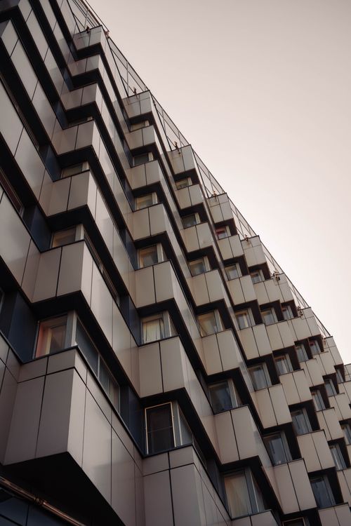 Free Low angle view of a modern skyscraper with a unique geometric facade in an urban setting. Stock Photo