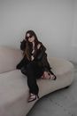 Woman in Black Jacket and Black Pants Sitting on Beige Sofa