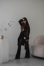 Woman in Black Long Sleeve Shirt and Black Pants Standing Beside White Wall