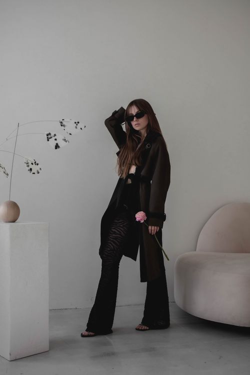 Free Chic portrait of a woman wearing sunglasses in a stylish outfit, holding a flower indoors. Stock Photo