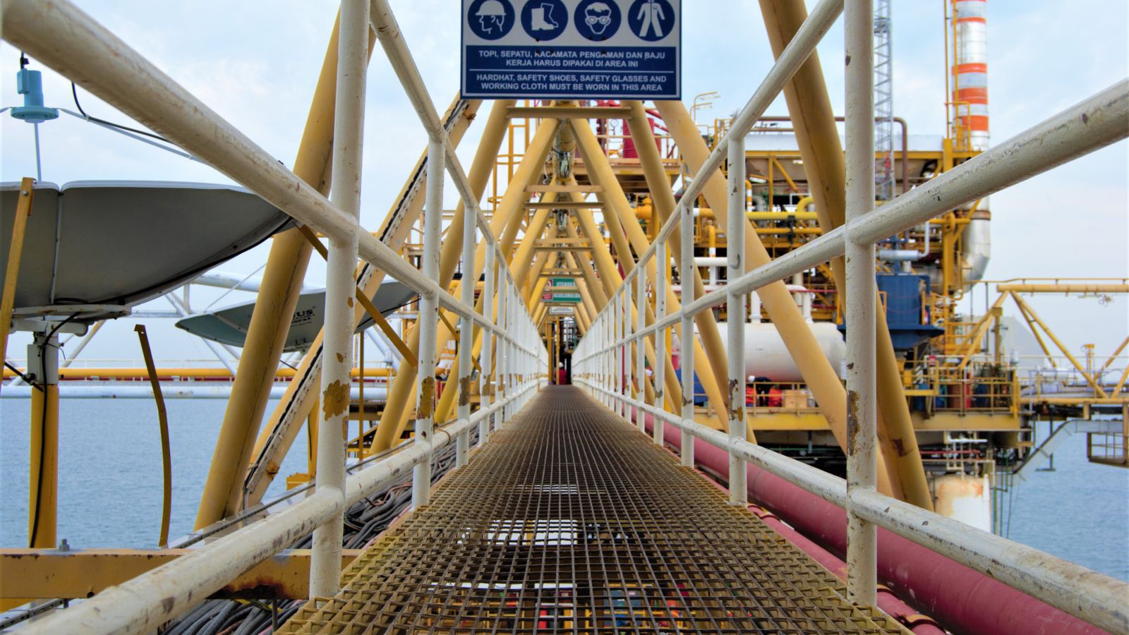 A steel walkway leading to an offshore oil platform in Indonesia, showcasing industrial architecture.