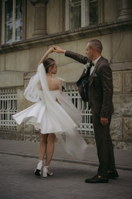 A newlywed couple elegantly dancing outside a historical building, capturing a romantic moment.