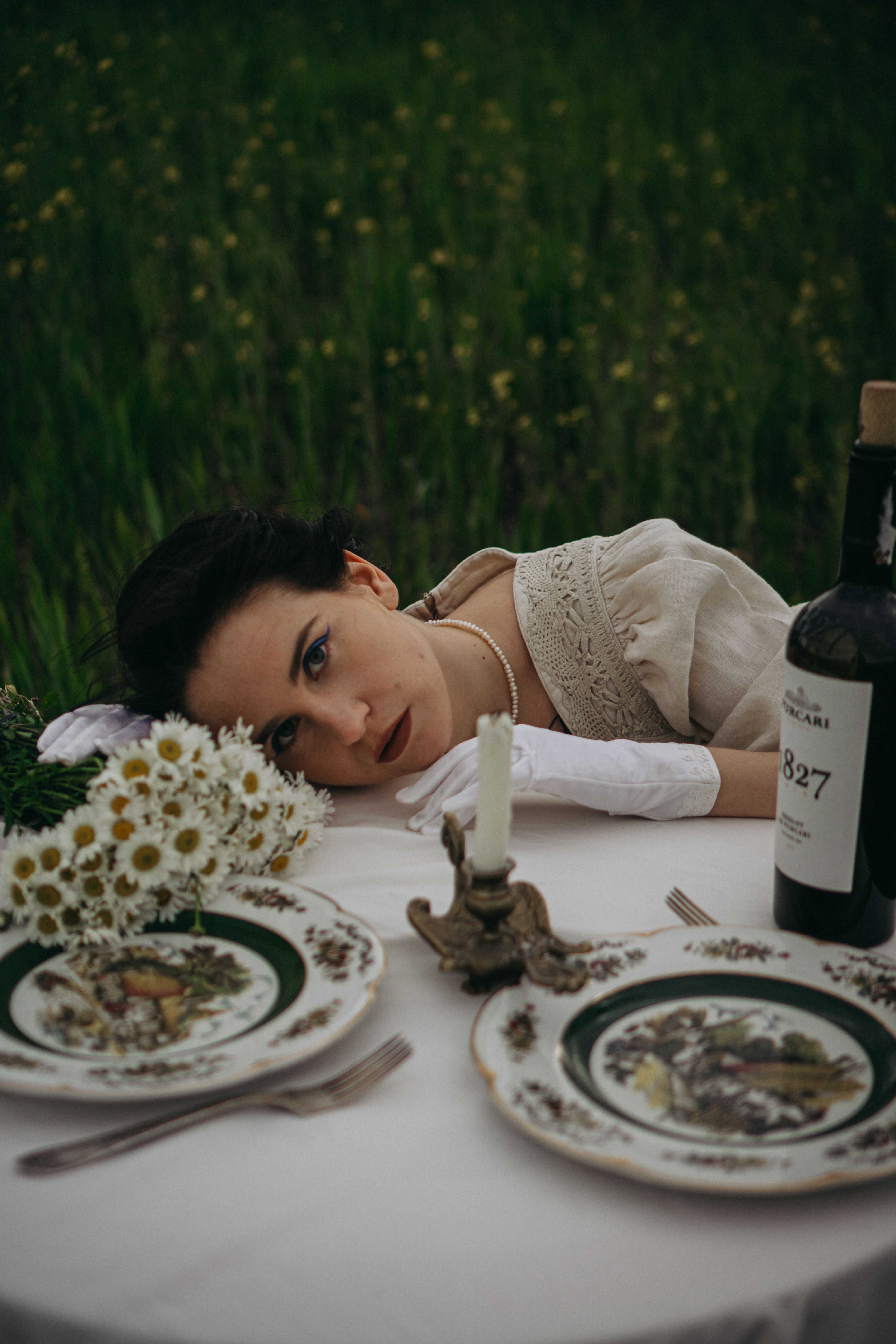Woman in vintage dress at elegant outdoor dinner table with flowers.