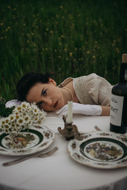 Woman in vintage dress at elegant outdoor dinner table with flowers.