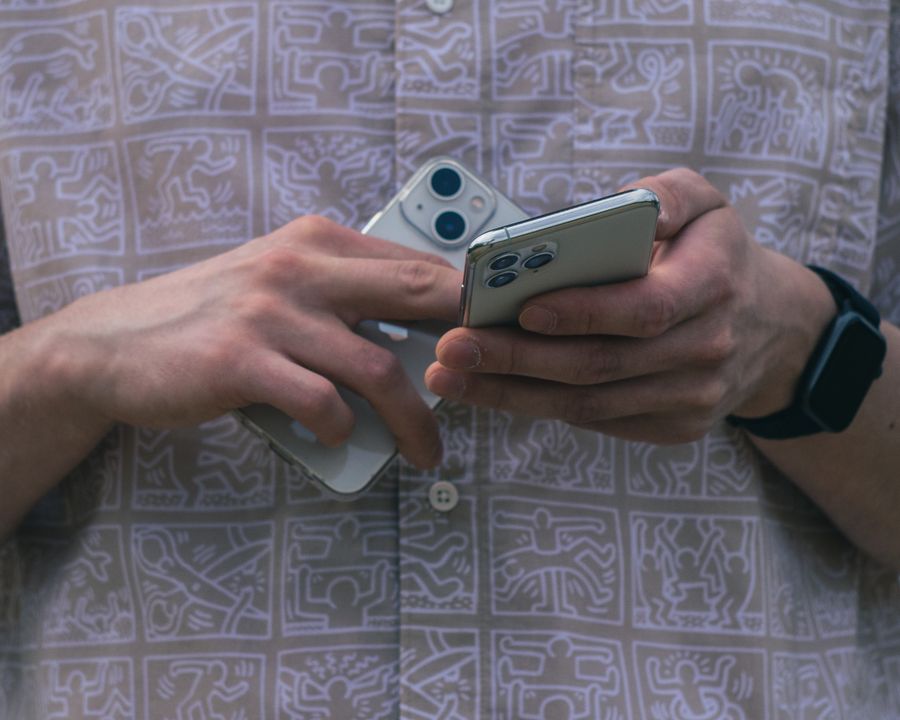 A person holding two smartphones to compare them