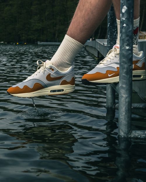 Free Close-up of Nike Air Max sneakers on a metal dock by a lake, showcasing modern style and comfort. Stock Photo