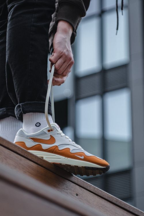 Free Close-up of a person tying sneakers in an urban environment. Stylish footwear on display. Stock Photo