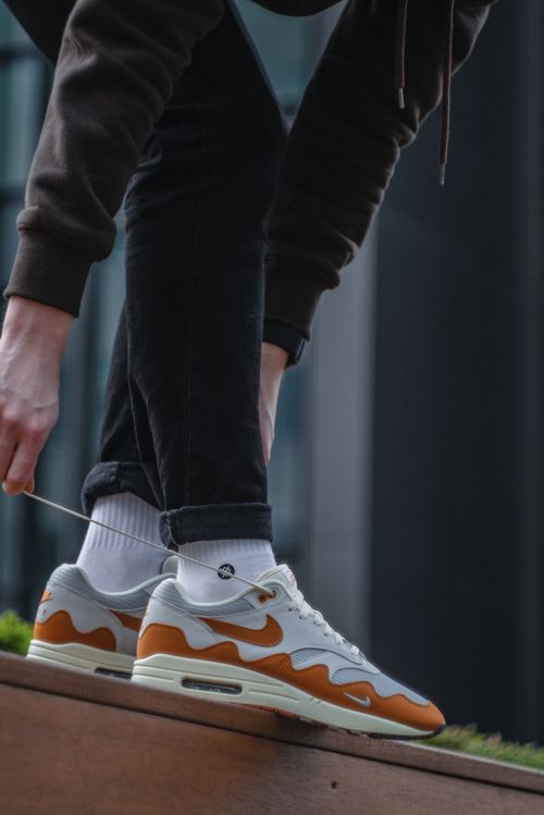 Free Close-up of an adult tying stylish sneakers outdoors. Stock Photo