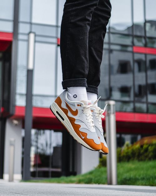 Free Stylish sneakers captured mid-air against a modern urban backdrop, showcasing street style and footwear trends. Stock Photo