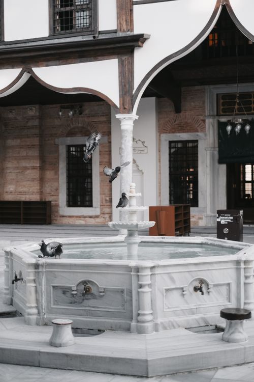 Free A beautiful fountain with pigeons in a historic courtyard in Bursa, Türkiye. Perfect for travel and architecture themes. Stock Photo