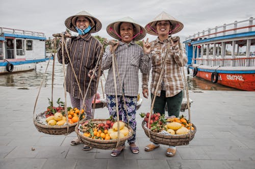 Free A Group of Women Wearing Hat while Carrying a Basket with Fruits Stock Photo