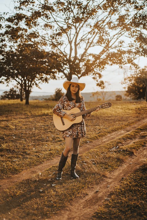 Woman Playing the Guitar in an Unpaved Road
