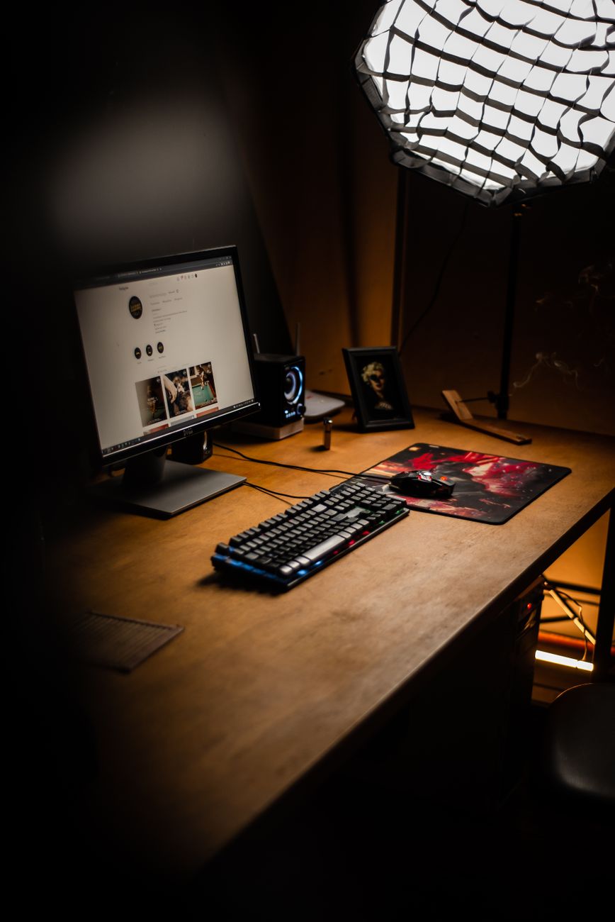 A minimalist desk setup featuring a monitor, keyboard, and mouse, under soft lighting, ideal for productivity.