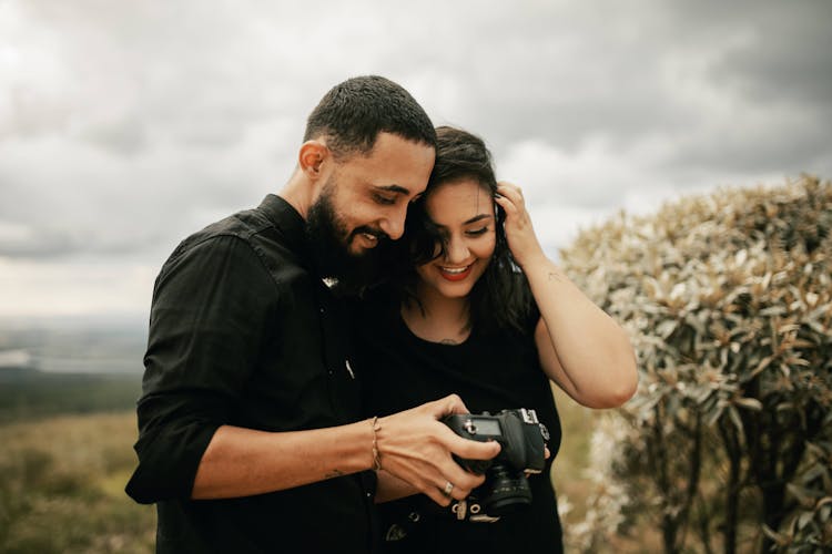 A Man And A Woman Looking At A Camera Together