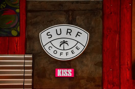 Close-up of a surf coffee shop sign with palm tree and colorful background.