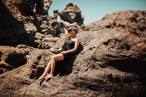 Free A woman in a black dress poses elegantly on rocky terrain in Karaburun, Izmir, Turkey. Stock Photo