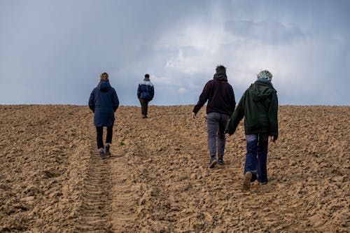 Free Group of People Walking on Brown Field Stock Photo