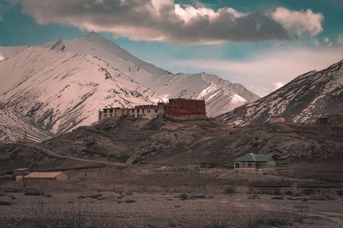 Free A solitary monastery sits beneath snow-covered peaks, offering a serene and isolated landscape. Stock Photo