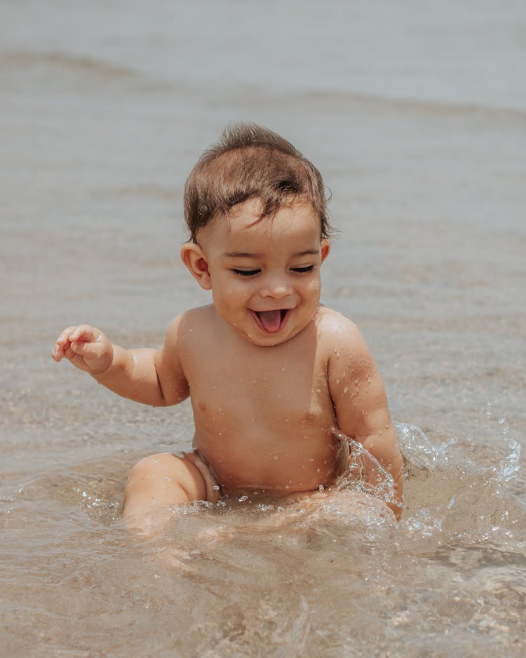 Baby Sitting In The Sea And Splashing Water 