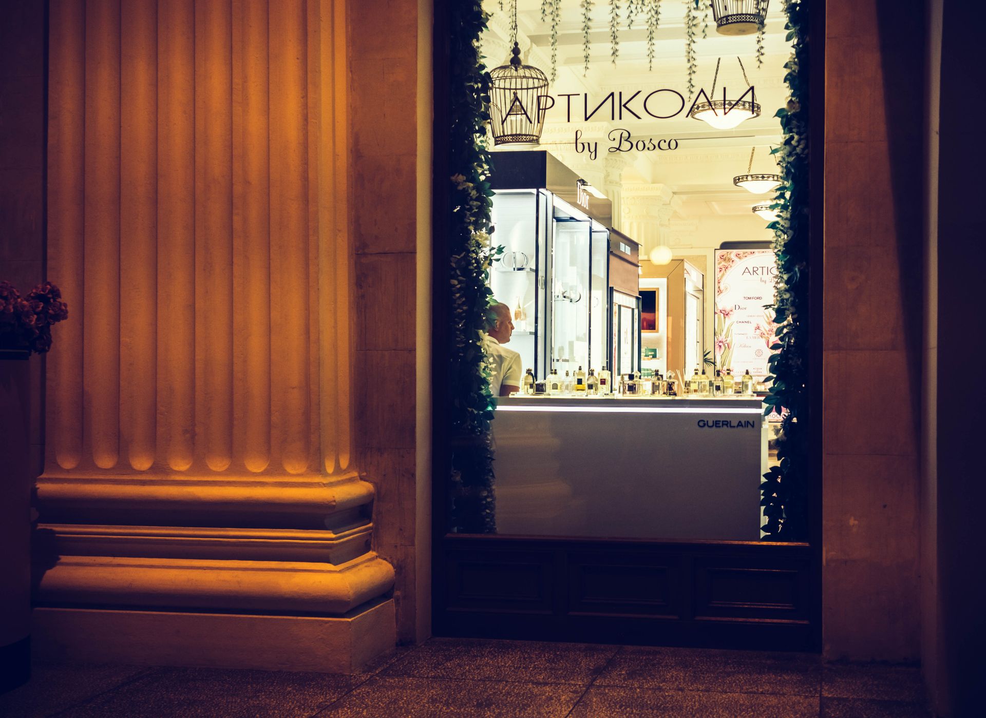 Elegant shop window display in Sochi at night, showcasing luxury perfumes and decorative lighting.