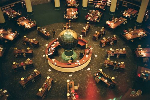 Free High-angle view of a library interior featuring a central globe and wooden tables, symbolizing knowledge and exploration. Stock Photo