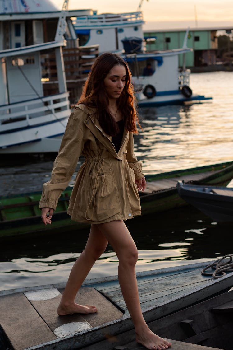 A Woman In Brown Coat Stepping On A Wooden Boat