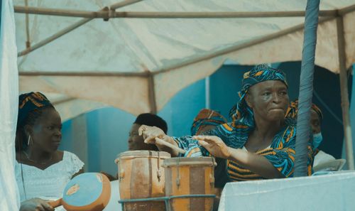 Free Elderly African woman passionately playing drums at a lively festival under a tent. Stock Photo