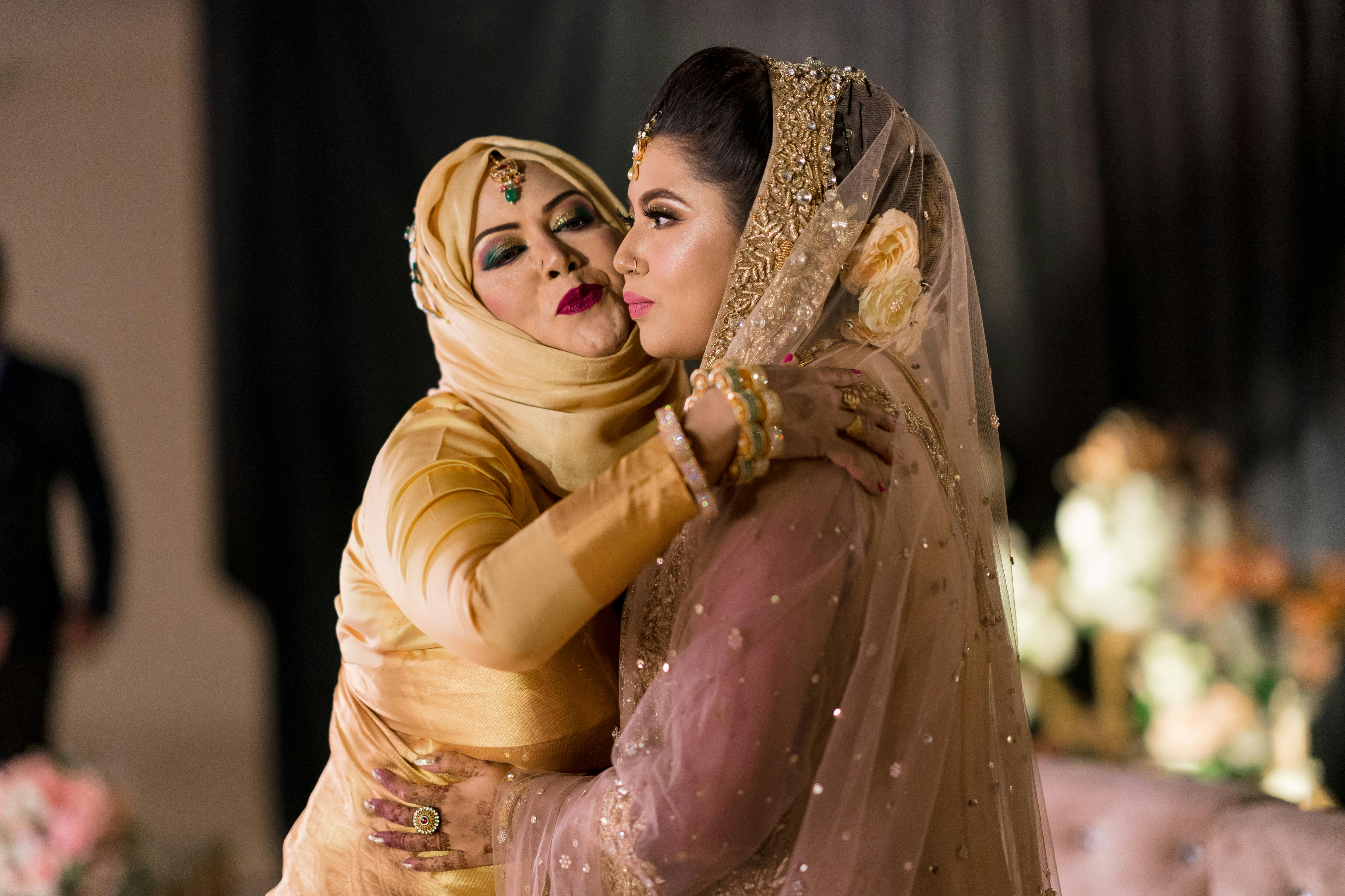 A heartfelt moment between a bride and her mother-in-law in traditional attire, capturing the essence of a wedding celebration.