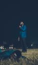 Man in Blue Dress Shirt and Black Pants Standing on Green Grass Field during Nighttime
