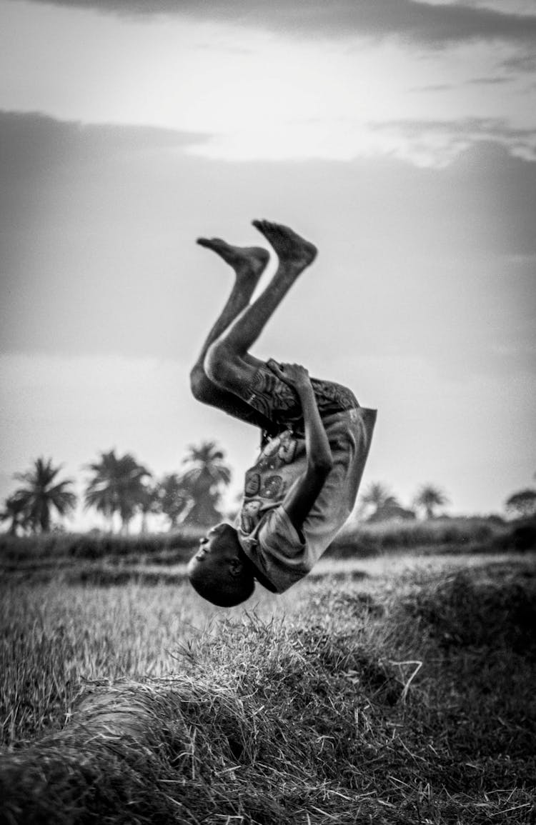 A Man Tumbling On Grass Field