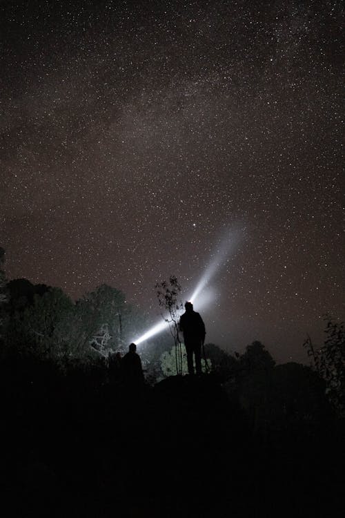 Silhouettes of Two People Standing under a Starry Night Sky 