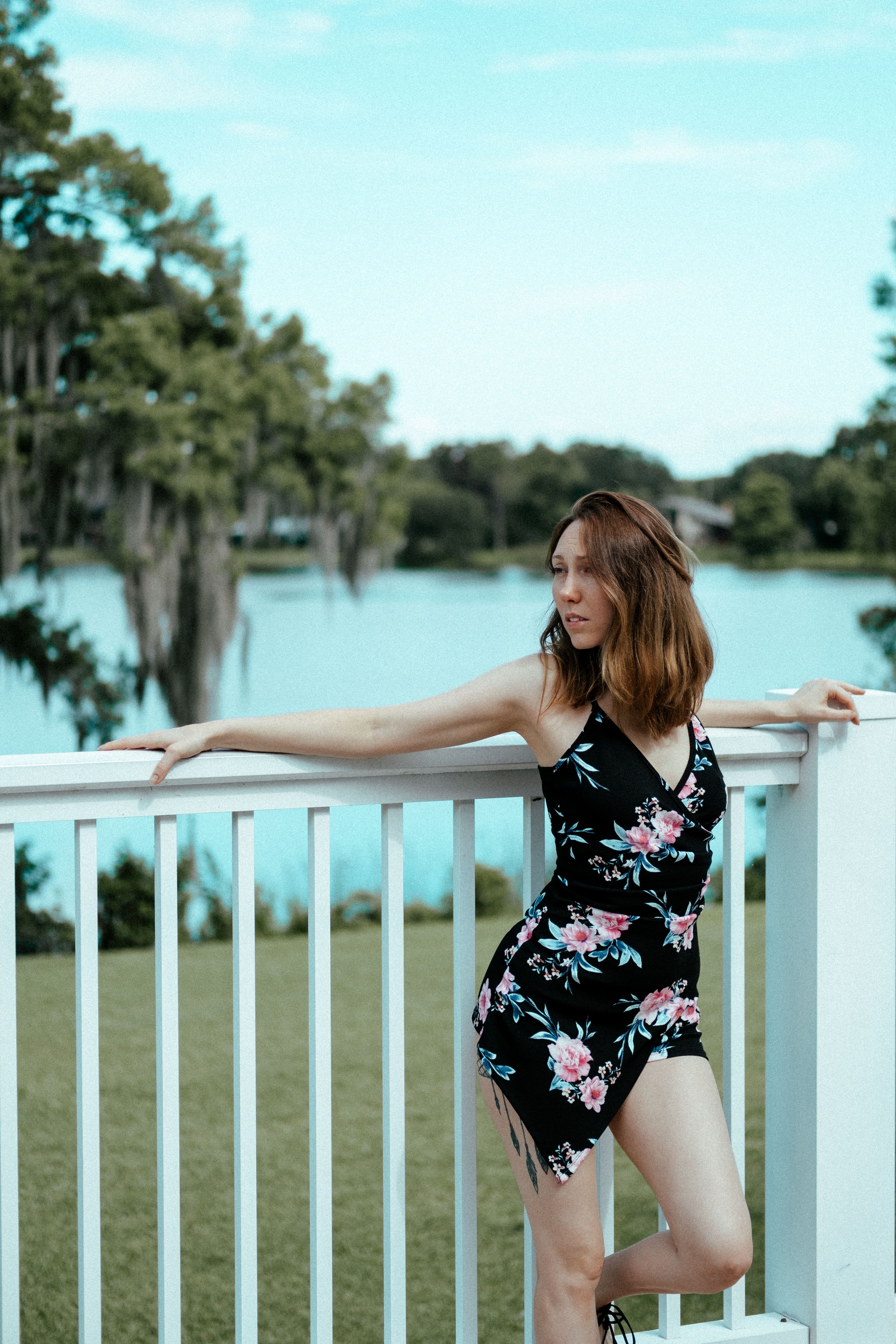 Woman in a Floral Dress Leaning on a White Railing · Free Stock Photo
