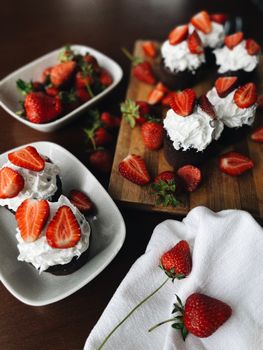 Indulge in rich chocolate cupcakes topped with whipped cream and fresh strawberries, captured in Turkey.