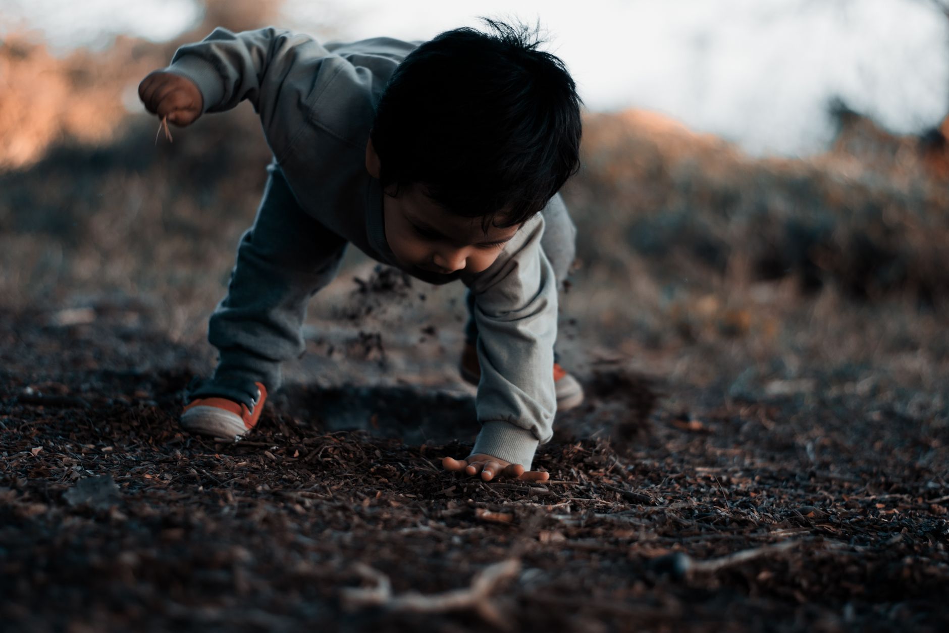 Young child playing with soil outdoors in Lima, capturing curiosity and exploration.