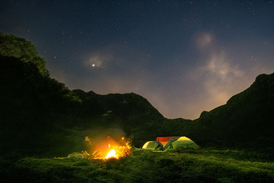 Tents pitched at a scenic camping site in Iceland with mountains in the background