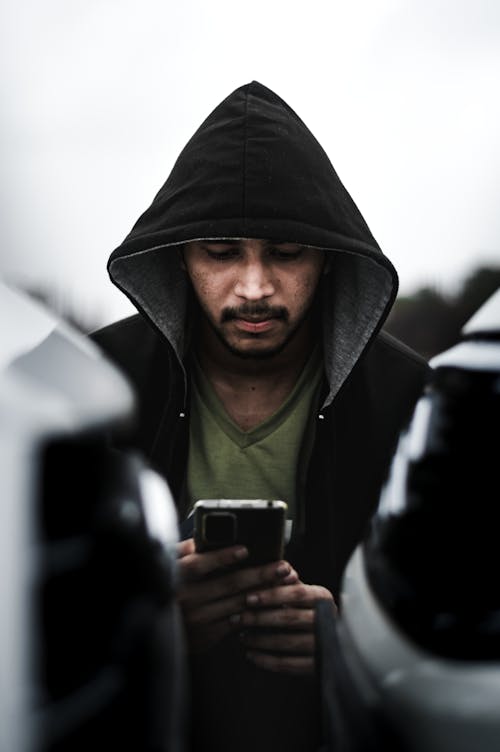 Free A Man in Black Hoodie Holding His Mobile Phone Stock Photo