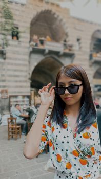 Stylish woman with sunglasses in a vibrant setting, exuding summer vibes.