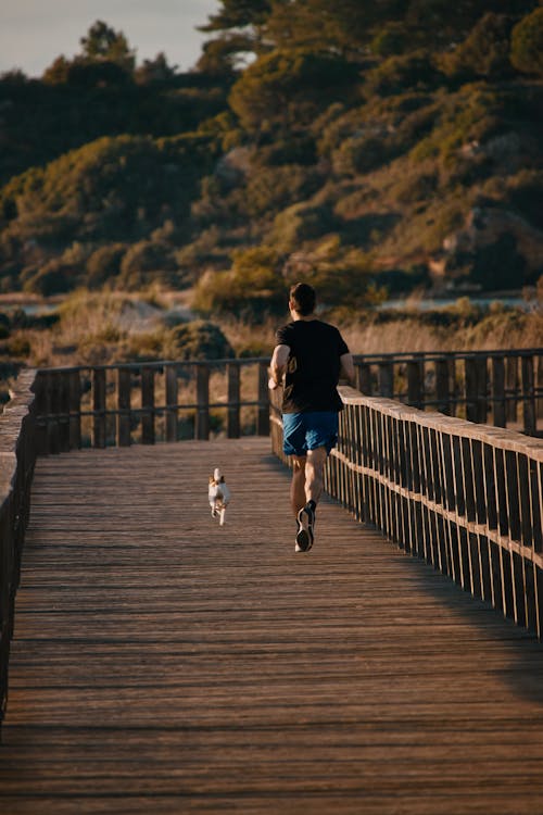 A Man in Black Shirt Jogging with His Dog