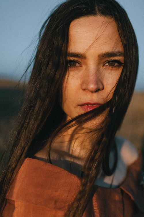 Free Close-up portrait of a woman with long hair in natural light, evoking a serene and pensive mood. Stock Photo