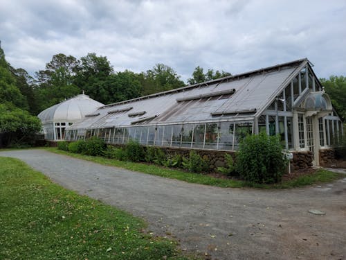 A Green House with Green Plants Under the Cloudy Sky